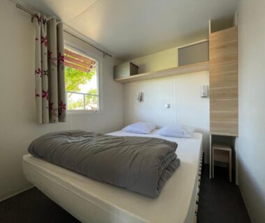 Chambre avec lit double et fenêtre dans le mobil-home de l'International Camping Ardèche