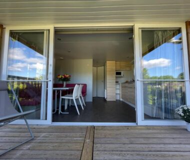 Terrasse en bois ouverte sur séjour avec table et chaises à l'International Camping Ardèche