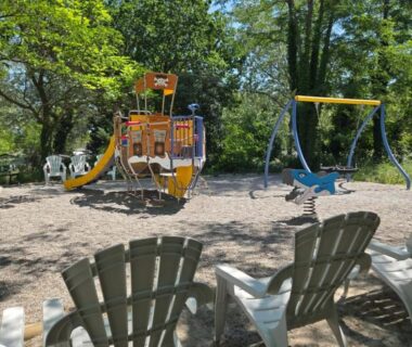 Aire de jeux ombragée avec balançoires et transats au camping Iscles 231- MH Au calme près du lac