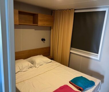 Chambre avec lit double store fermé et serviettes pliées dans le JP L'Eleganzia 2 ch clim réversible Confort et Elégance