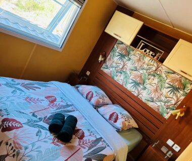 Chambre avec lit double et serviettes dans le Joli Mobil-Home de Vacances