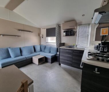 Intérieur salon avec canapé d'angle et kitchenette du Joli mobil home 4-6 personnes 416