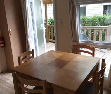 Coin repas intérieur avec table et chaises et terrasse visible du KERLANN****MOBIL-HOME 4 CH TOUT CONFORT