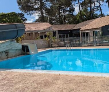 Piscine extérieure avec toboggan et bâtiments en arrière-plan au Kabana La palmeraie confort détente assurée 7 kms plages