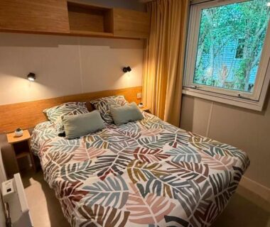 Chambre avec lit double et fenêtre donnant sur la végétation au Kélya Lodge