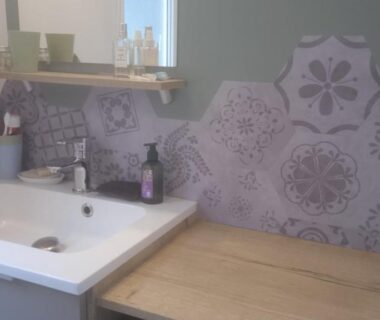 Salle de bains avec lavabo plan de travail en bois et crédence à motifs du camping Kerlann