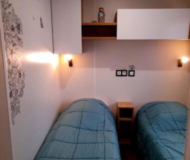Chambre avec deux lits simples et luminaires muraux dans le camping L EVASION
