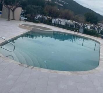 Piscine et terrasse avec mobil-homes en arrière-plan au camping L éden