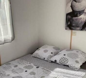 Chambre avec lit double et tableau près de la fenêtre dans le camping L éden