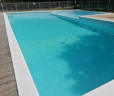 Piscine extérieure bordée d'une terrasse en bois au camping L escale de larcher