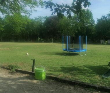 Espace vert avec trampoline et filet de jeux au camping L escale de larcher