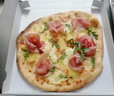 Boîte de pizza garnie de jambon et roquette au camping L escale de larcher