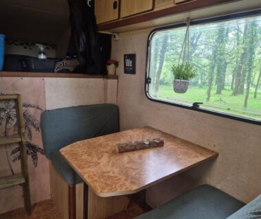 Intérieur de caravane coin repas près de la fenêtre du camping L insolite