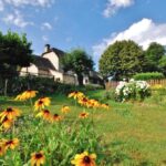 Jardin fleuri et pelouse avec chalets en arrière-plan au camping LA VIEILLE AUBERGE