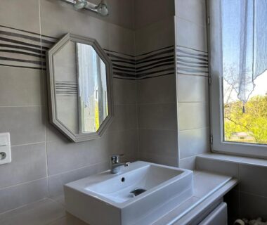 Salle de bain avec lavabo miroir et fenêtre au camping LA VIEILLE AUBERGE