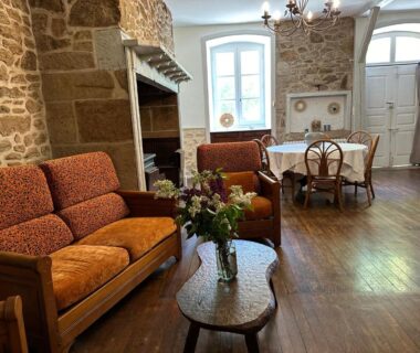 Salon rustique avec canapés et cheminée dans LA VIEILLE AUBERGE
