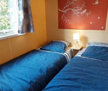 Chambre avec deux lits simples et lampe près de la fenêtre au camping LAVATOGGIO