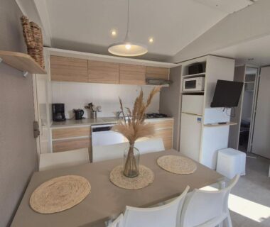Intérieur avec table, chaises et kitchenette du L'Azura Mobil Home 6 personnes