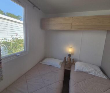 Chambre avec deux lits et lampe dans le mobil home L'Azura Mobil Home 6 personnes Les Dunes
