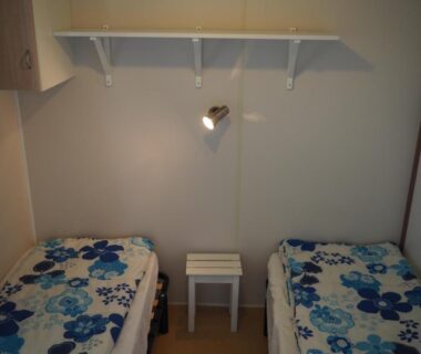 Chambre avec deux lits simples et table de chevet au camping LE CASQUE ROI