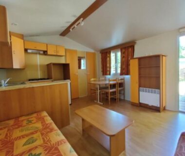 Intérieur séjour avec kitchenette et canapé dans le mobil home LE CORNOUILLER au CAMPING LE BEL AIR