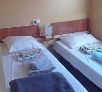 Chambre avec deux lits et serviettes dans le mobil home Le Figuier