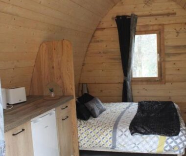 Intérieur en bois avec lit et kitchenette dans la cabane Le Fresne