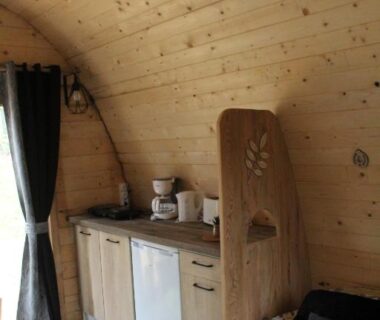 Intérieur en bois avec kitchenette et lit dans la cabane Le Fresne