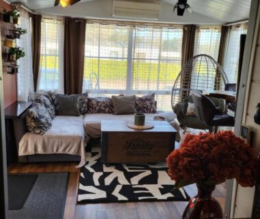 Salon avec canapé et fauteuil suspendu dans le logement du camping Le Petit Bonheur