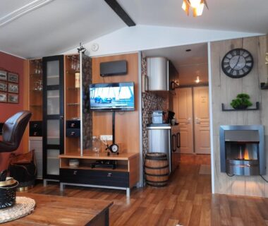 Séjour intérieur avec télévision poêle et coin cuisine dans le logement Le Petit Bonheur