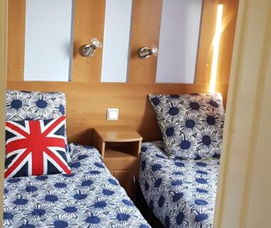 Chambre avec deux lits liseuses et étagères au camping LE PETIT BONHEUR