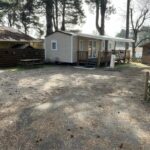 Allée gravillonnée et mobil-home sous pins au camping LE PIPA