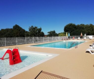 Piscine extérieure avec pataugeoire et transats au camping LES PIERRES CHAUDES