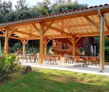 Terrasse couverte avec tables et chaises au camping LES PIERRES CHAUDES