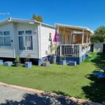 Terrasse et pelouse devant un mobil home au camping L'Exellence