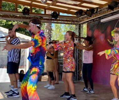 Scène extérieure avec artistes en costumes colorés au camping L'Exellence