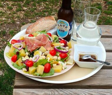 Table de terrasse avec salade, pain et bière au mobil-home L'OLIVIER