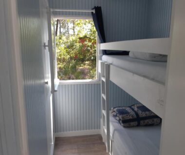 Chambre avec lits superposés et fenêtre sur les arbres au Loue joli chalet en bois