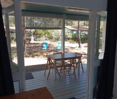 Terrasse en bois avec table et chaises au LOUE JOLI CHALET EN BOIS au CHM de MONTALIVET