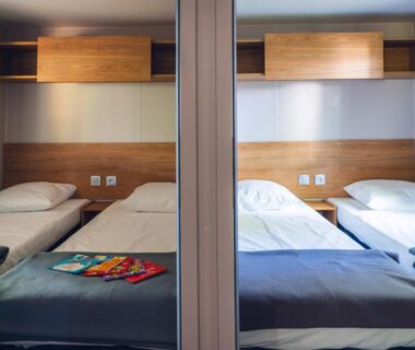 Chambre avec deux lits et mobilier bois au camping L'Oasis des Dombes