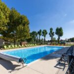 Piscine extérieure bordée de transats au camping L'Oasis des Dombes