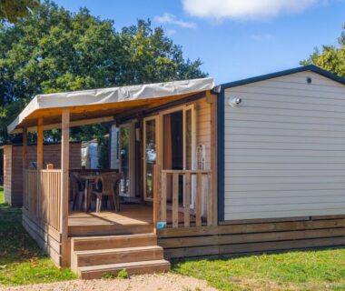Mobil-home avec terrasse en bois et table et chaises au camping L'Oasis des Dombes