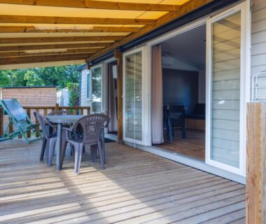 Terrasse couverte avec table chaises et transats du logement L'Oasis des Dombes