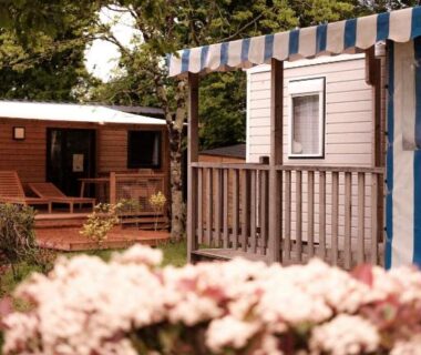 Terrasse et mobil-homes entourés d'arbres au camping L'Orée de l'Océan