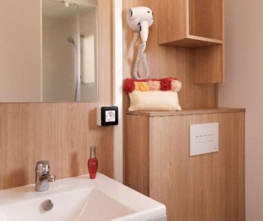 Salle de bain avec lavabo miroir et sèche-cheveux dans le mobil-home L'Orée de l'Océan