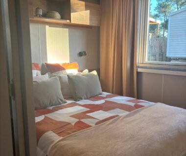 Chambre avec lit double et fenêtre sur extérieur boisé dans le mobil home L'Orée des Pins Cap Ferret