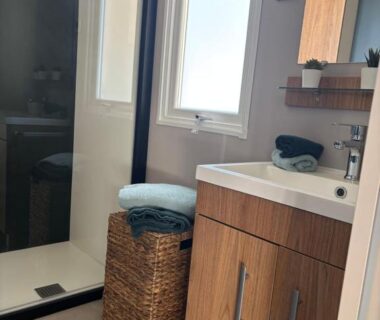 Salle d'eau avec douche vitrée meuble vasque et panier en osier du mobil home L'Orée des Pins Cap Ferret