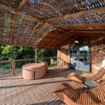 Terrasse en bois avec spa transats et fauteuil suspendu à La Buissonnière Lodges