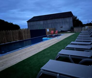 Bord de piscine avec transats et terrasse en bois au camping La Buissonnière Lodges