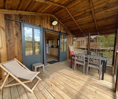 Terrasse en bois avec chaises longues et table à manger de La Buissonnière Lodges